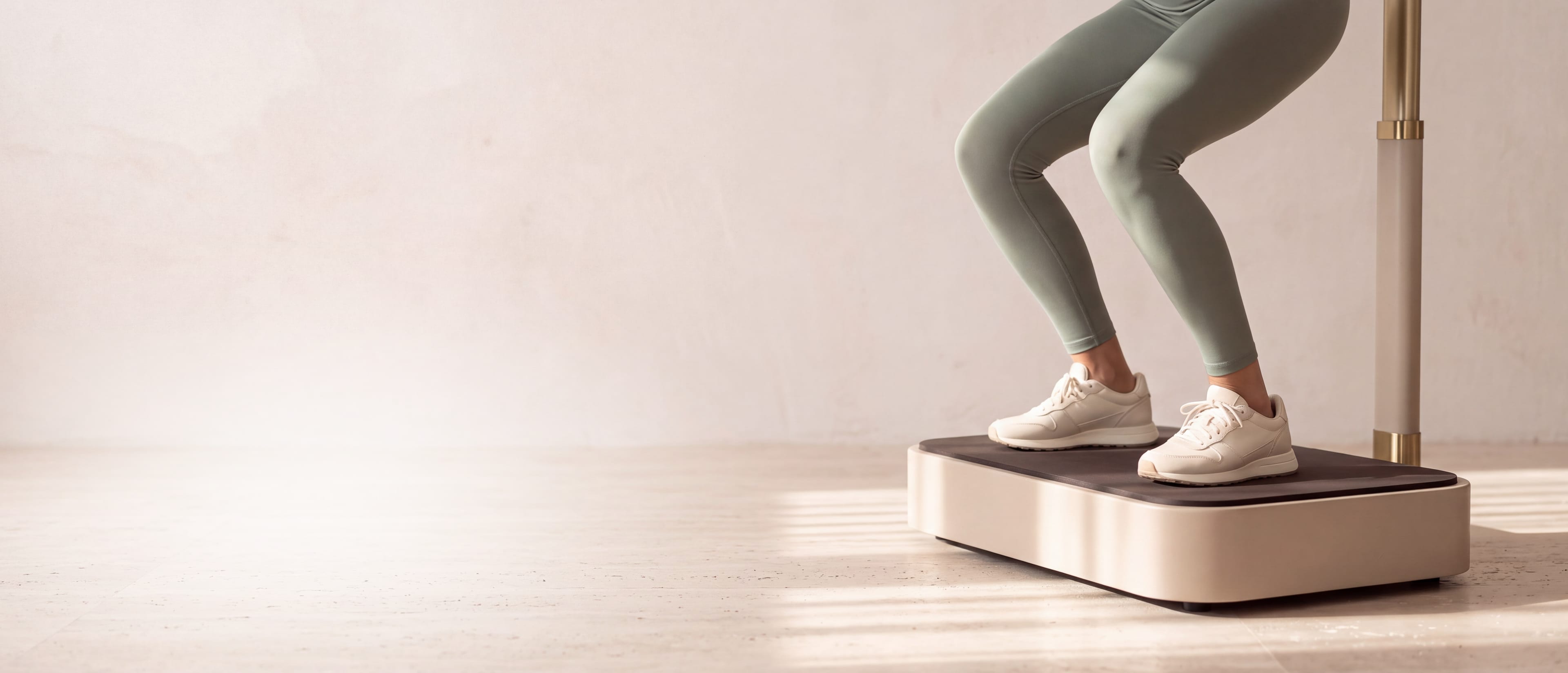 Beine in salbeigrünen Leggings in der Kniebeuge auf einer Vibrationsplatte