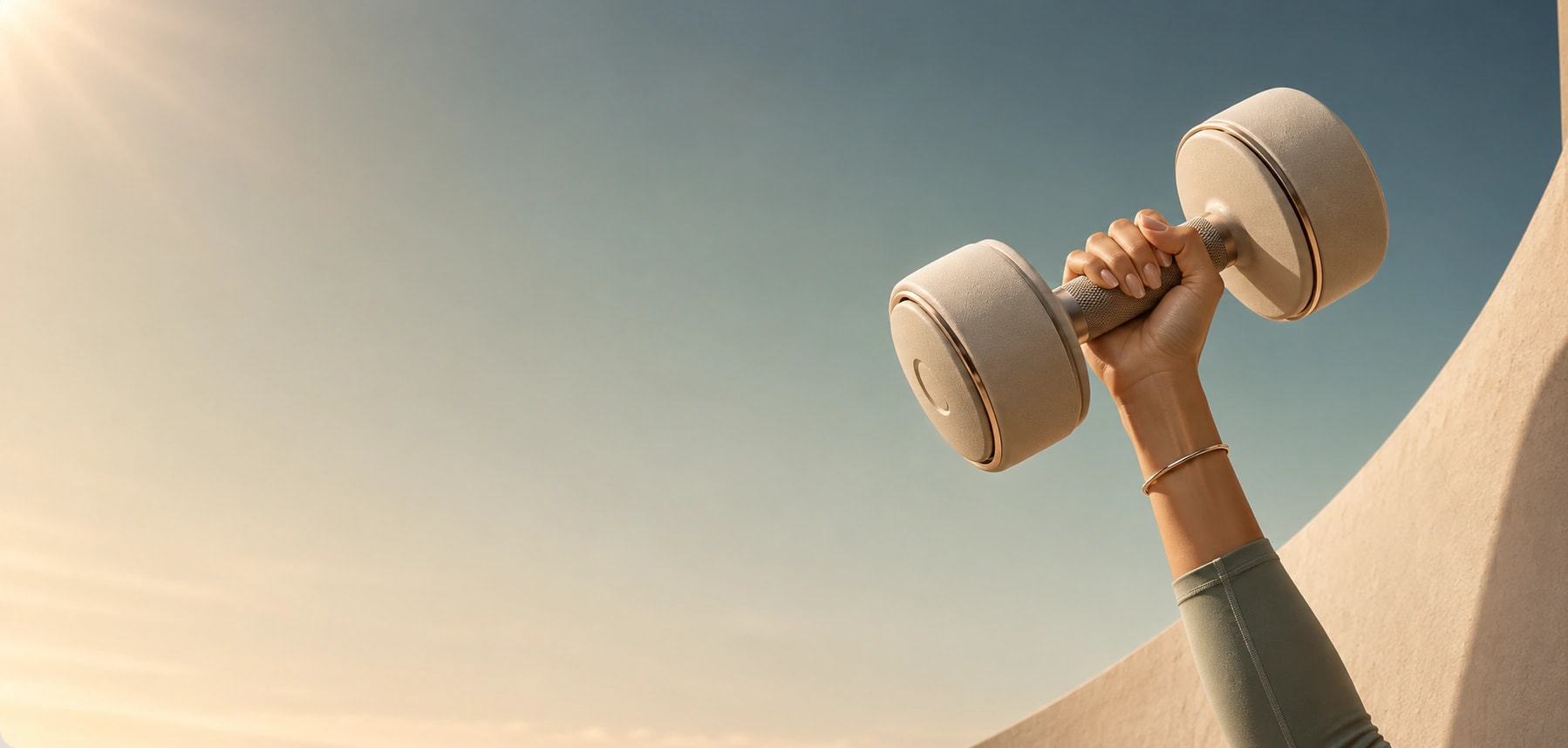 An arm in a green sleeve lifts a dumbbell towards the sky